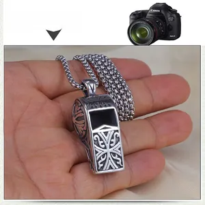 Detailed view of vintage stainless steel whistle pendant with intricate cross engravings