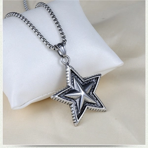 Macro detail of silver star pendant on a box chain displayed on a white soft pillow