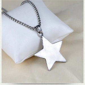 Macro detail of stainless steel star pendant with box chain on jewelry cushion
