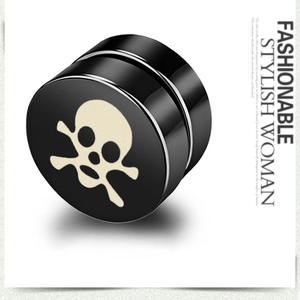 Macro shot of black magnetic skull earring with white crossbone design on polished steel