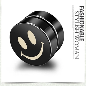 Macro view of black magnetic stud earring with cream smiley face icon on stainless steel