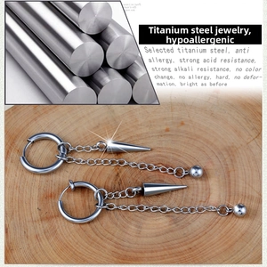 Detail of titanium steel tassel earrings with double chains and cone pendants on wood