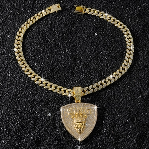 Gros plan du pendentif hip hop doré avec tête de lion couronnée et inscription KING
