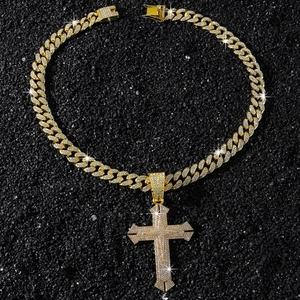 Gros plan sur la chaîne cubaine dorée hip hop avec pendentif croix givré sur fond de pierre
