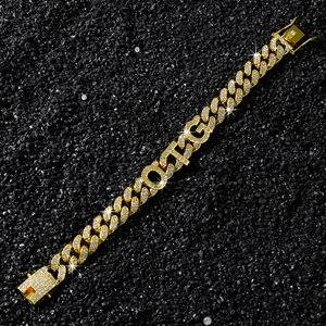 Gros plan d'un bracelet gourmette doré avec lettres OTG et strass brillants sertis