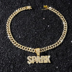 Gros plan d'une chaîne cubaine plaquée or et pendentif SPARK avec cristaux brillants