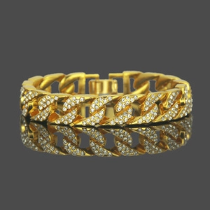 Macro detail of gold Cuban link bracelet with iced-out crystals and square clasp