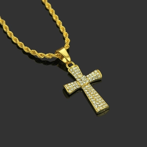 Gros plan d'un pendentif croix hip hop avec strass et chaîne de corde dorée en gros plan