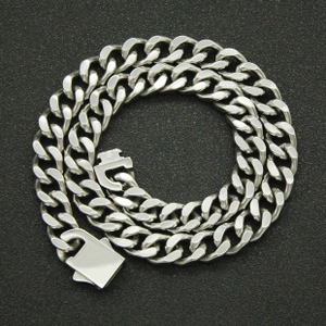 Close-up of a silver Cuban link chain with a thick square buckle on a dark textured background