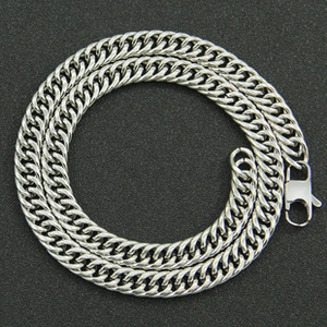 Close-up of silver punk cuban chain necklace with lobster clasp on textured surface