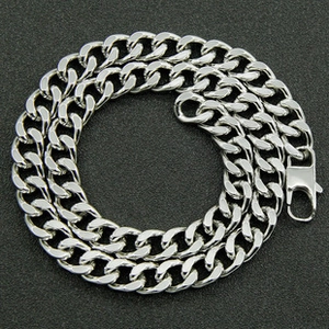 Detail of silver Cuban link chain with lobster clasp on a textured grey background