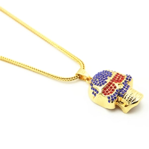 Detail of hip hop skull pendant with blue and red crystals on a gold wheat chain