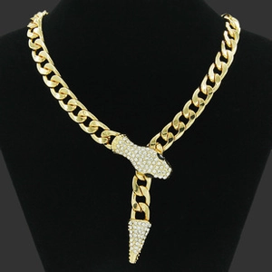 Detailed view of a gold curb chain necklace featuring a pavé rhinestone snake head pendant