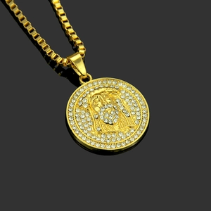 Close-up of golden Jesus portrait pendant with pave-set crystals on a black reflective surface