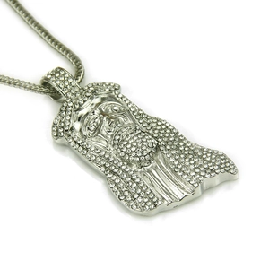 Macro detail of silver Jesus pendant with shimmering pavé set rhinestones on white background