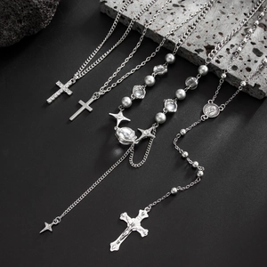 Vue détaillée de pendentifs croix en argent et chaînes de chapelet sur pierre sombre