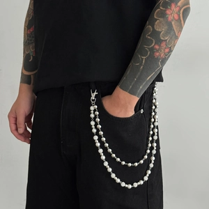 Double-layer pearl and silver bead trousers chain worn on black denim jeans