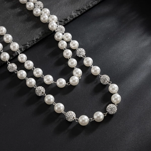 Detail of luxury pearl trousers chain with sparkling rhinestone beads on dark rock surface