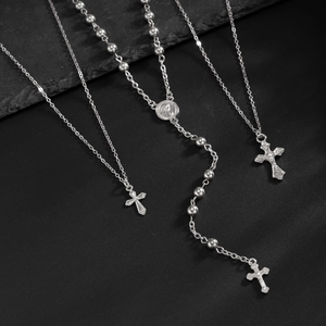 Détails des pendentifs en croix argentée et perles de chapelet sur ardoise noire