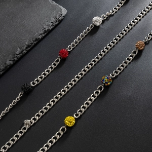 Détail de chaînes à maillons argentés avec perles disco multicolores en strass sur fond gris