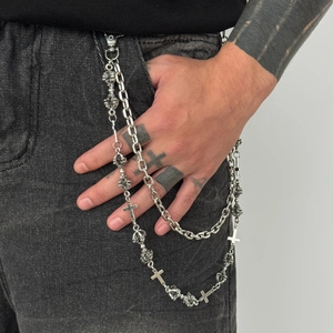 Detail of silver alloy cross wallet chain with vintage beads on black denim jeans
