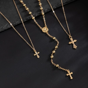 Gros plan de trois colliers religieux dorés avec des croix et une médaille de saint