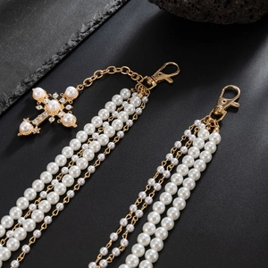 Detail of multi-layer pearl trouser chain with crystal cross pendant and gold clasp