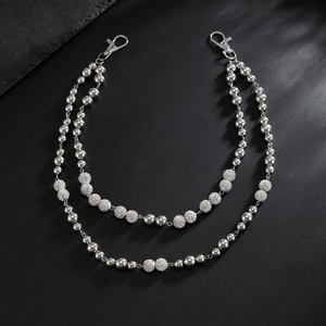 Detail of double-layer silver beaded pants chain with lobster clasps on black stone background