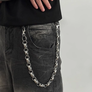 Close-up of retro silver skull chain links on black denim pants with metal lobster clasps