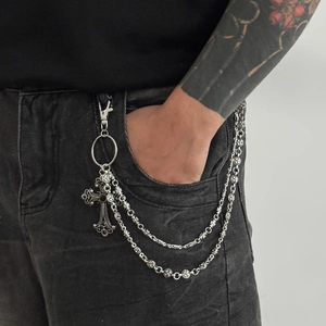 Detail of vintage gothic double-layer wallet chain with floral rings and cross on jeans