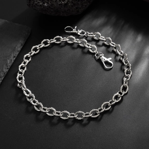 Detail view of silver O-chain with lobster clasps and textured metal rings on dark rock
