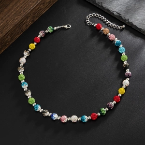 Gros plan du collier de perles en strass colorés avec intercalaires sur fond texturé