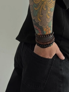 Detail of men's layered leather and wood bead bracelets worn on arm with vintage style
