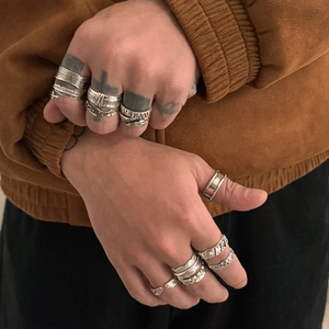 Close-up of vintage silver men's feather and cross ring set worn on hand