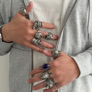 Detail of vintage silver rings with skull, lion head, and blue gemstone on male hands