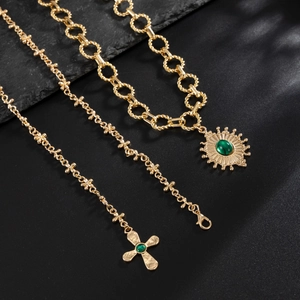 Detailed view of vintage gold-plated cross necklace with emerald-green gemstones