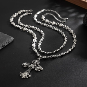 Detail view of retro silver cross pendant with hollow patterns and sparkling crystals