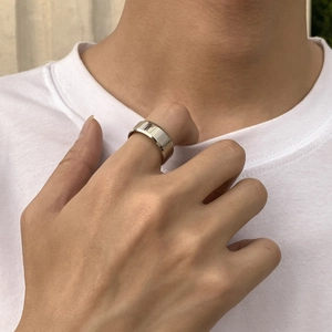 Gros plan d'une large bague en acier titane poli portée à l'index pour un look minimaliste