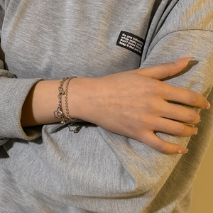 Detail of a double-layer stainless steel silver bracelet with hollow flower charm on wrist