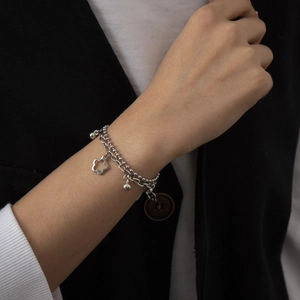 Detailed macro view of silver double-layer bracelet with hollow flower and ball charms