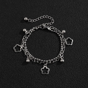 Detail of silver double-layered chain bracelet with floral charms on black leather