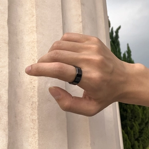Gros plan d'une bague intelligente en titane noir poli portée à l'index masculin