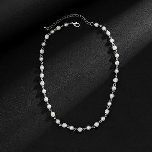 Close-up of pearl necklace with pavé diamond beads on black leather background