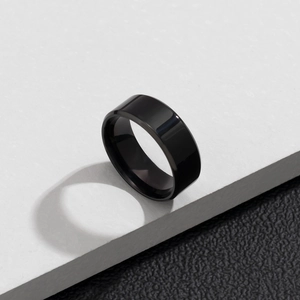 Gros plan d'une bague minimaliste en acier titane noir sur un support en marbre