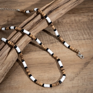 Bohemian beaded necklace with brown wood texture and metal clasp on wooden display