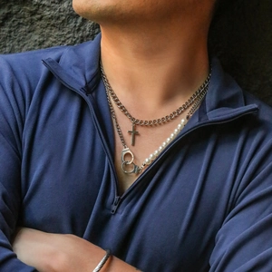 Detail of layered cross and freedom handcuff pendant necklace with pearl stitching