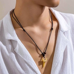 Détail d'un pendentif dent de requin avec perles en bois sur cordon noir sur chemise