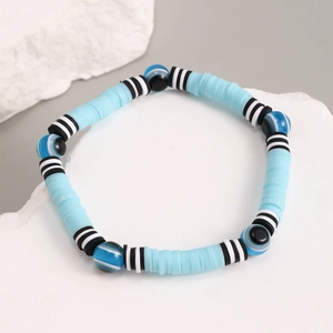 Close-up of bohemian blue heishi beads and evil eye resin charms on a beaded bracelet