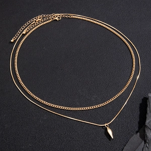 Close-up of double-layer gold necklace featuring a conical stud pendant and Cuban chain