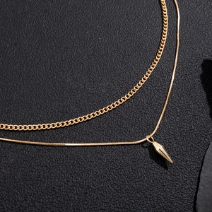Gold double layer necklace with flat curb chain and a polished spike pendant on black leather